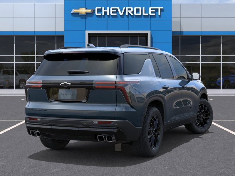 Vue arrière trois quarts d’un Chevrolet Traverse bleu devant une concession Chevrolet, mettant en valeur les feux arrière horizontaux, les jantes noires et le design moderne et robuste du VUS familial.