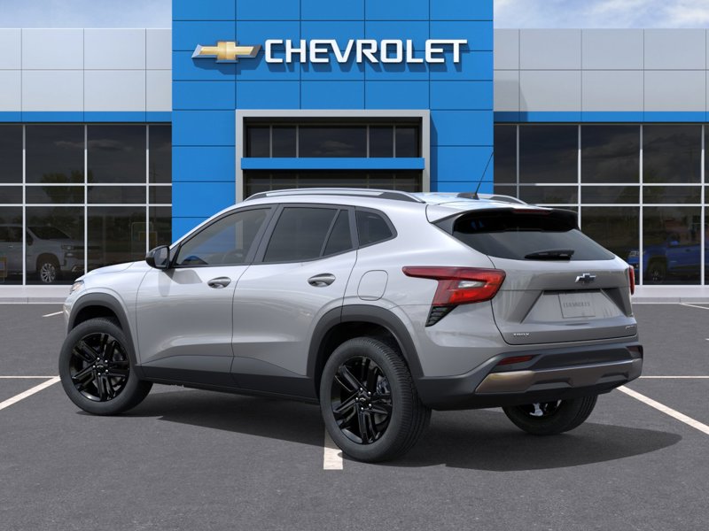 Vue arrière trois quarts d’un Chevrolet Traverse argent stationné devant une concession Chevrolet, mettant en valeur les feux arrière DEL, les jantes noires et le design spacieux et moderne du VUS familial.