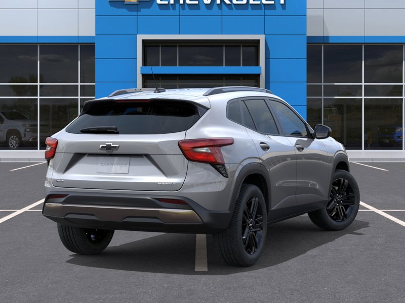 Vue arrière trois quarts d’un Chevrolet Traverse argent devant une concession Chevrolet, mettant en valeur les feux arrière modernes, les jantes noires et le design robuste et élégant du VUS.